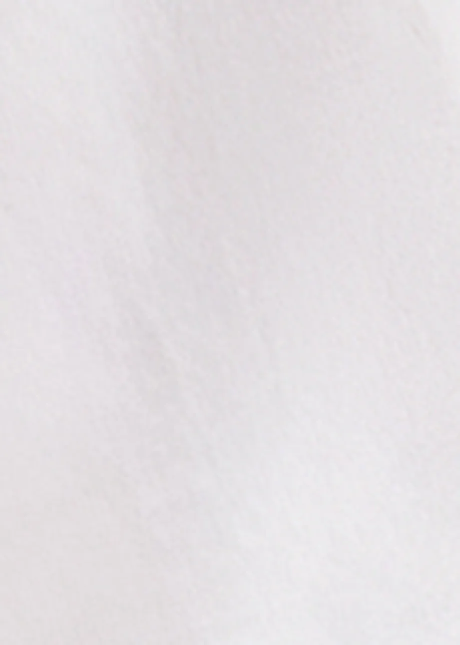 White cotton top with ruffle details, voluminous sleeves, and self-tie collar