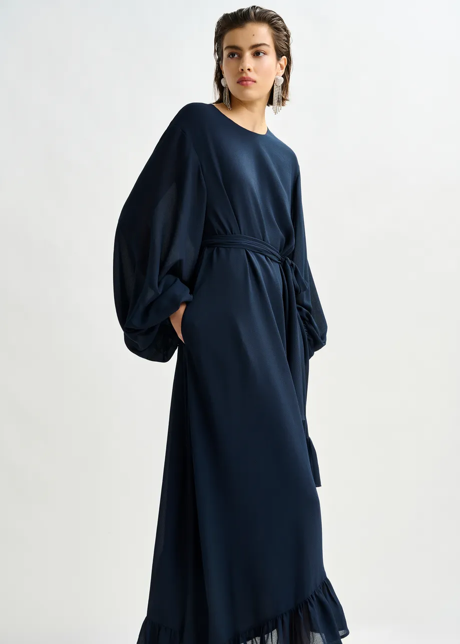 Donkerblauwe asymmetrische maxi-jurk met ruches aan de zoom en strikdetail bij de hals