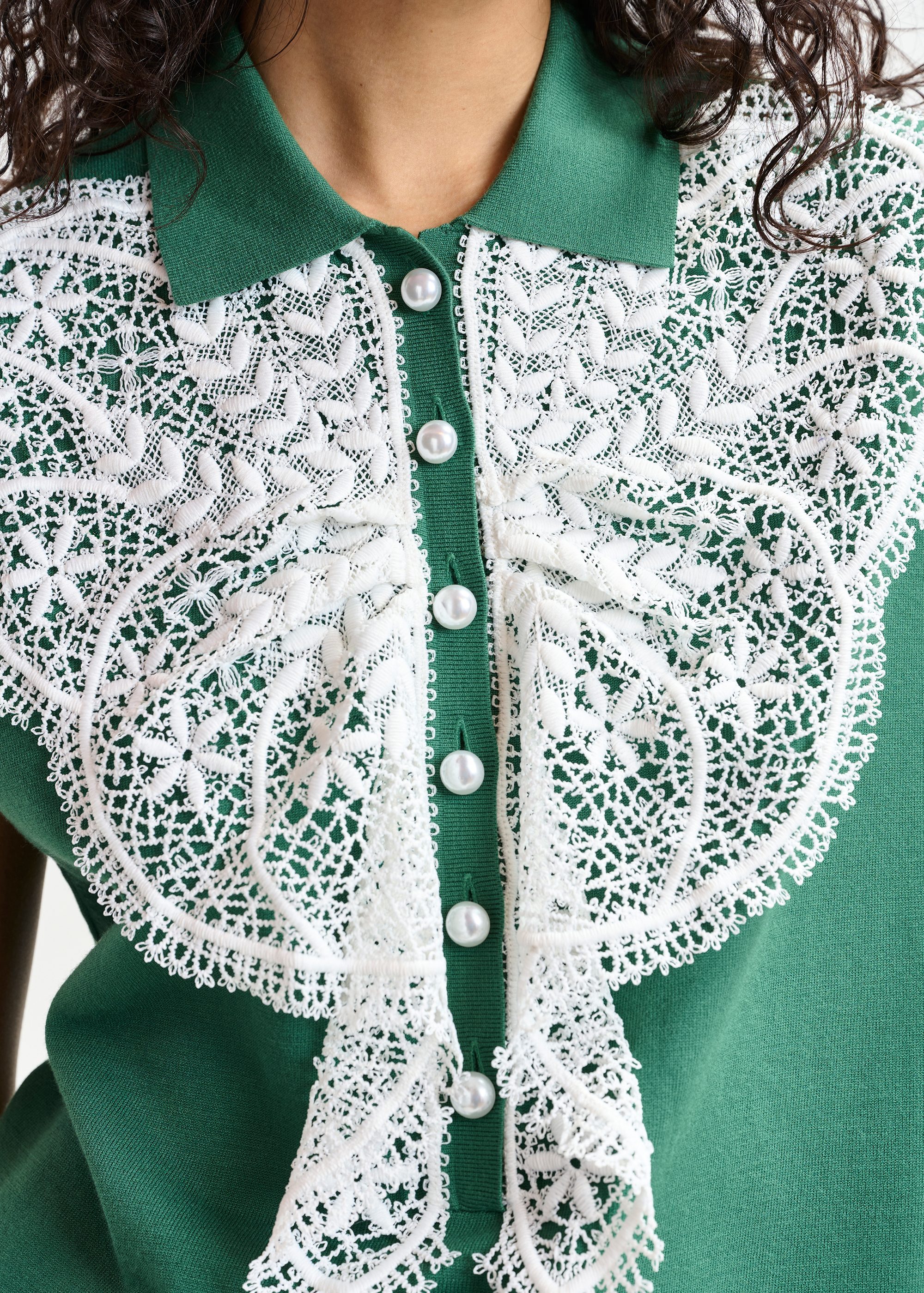 Green and white sleeveless polo with lace details and pearl