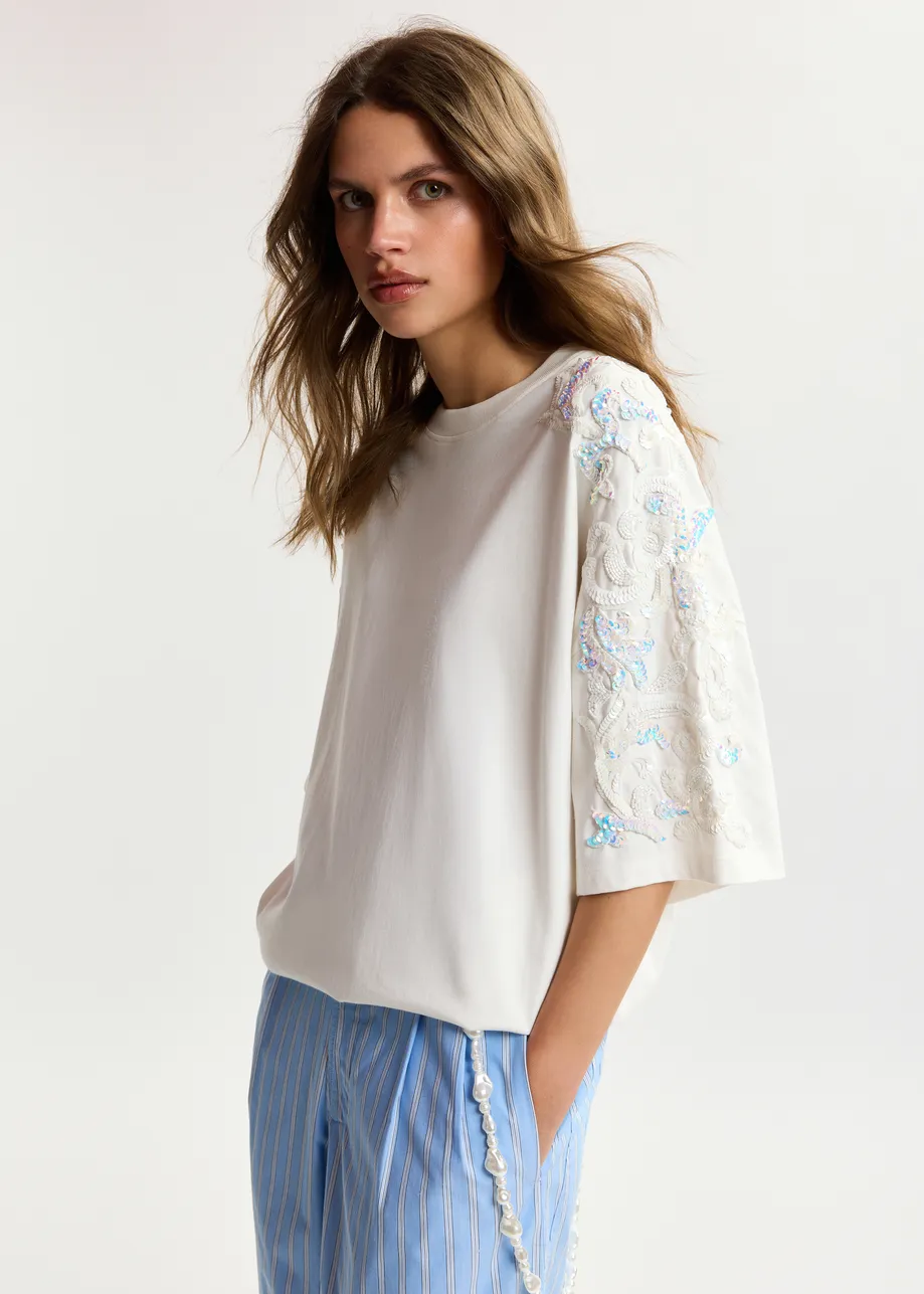T-shirt in cotone avorio chiaro  con decorazioni in paillettes e perline