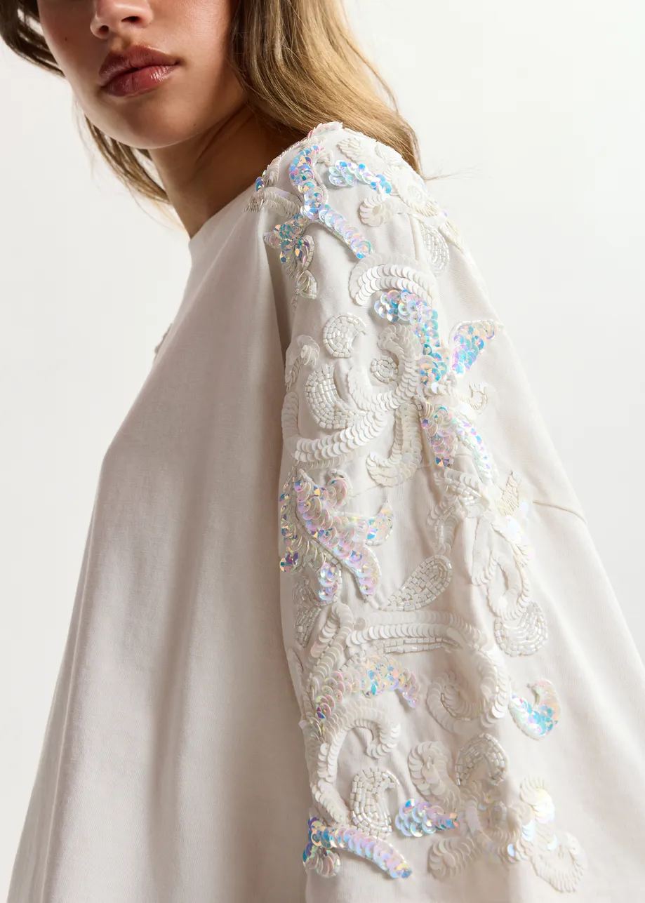T-shirt in cotone avorio chiaro  con decorazioni in paillettes e perline
