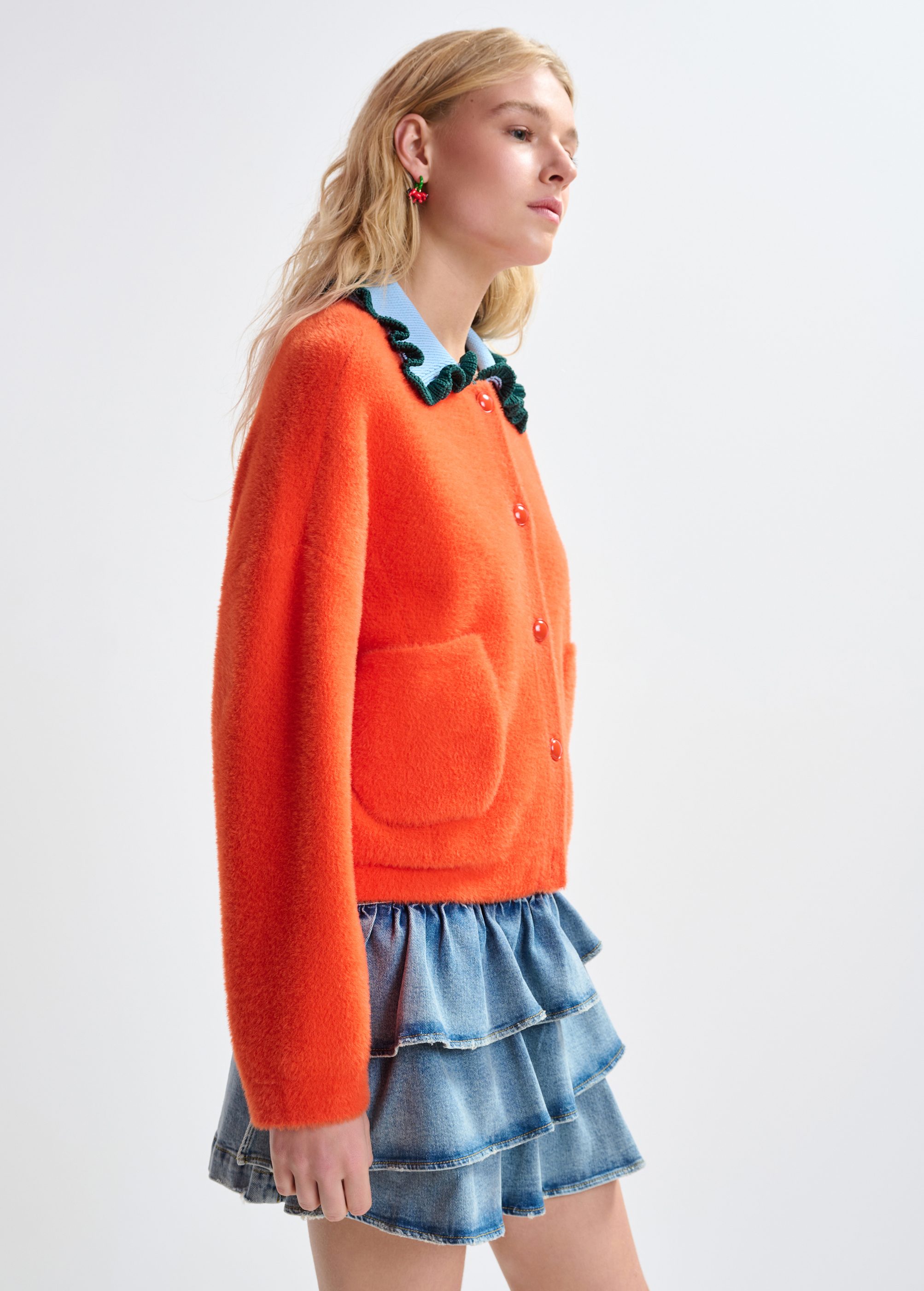Orange cardigan with contrasting light blue and dark green ruffle