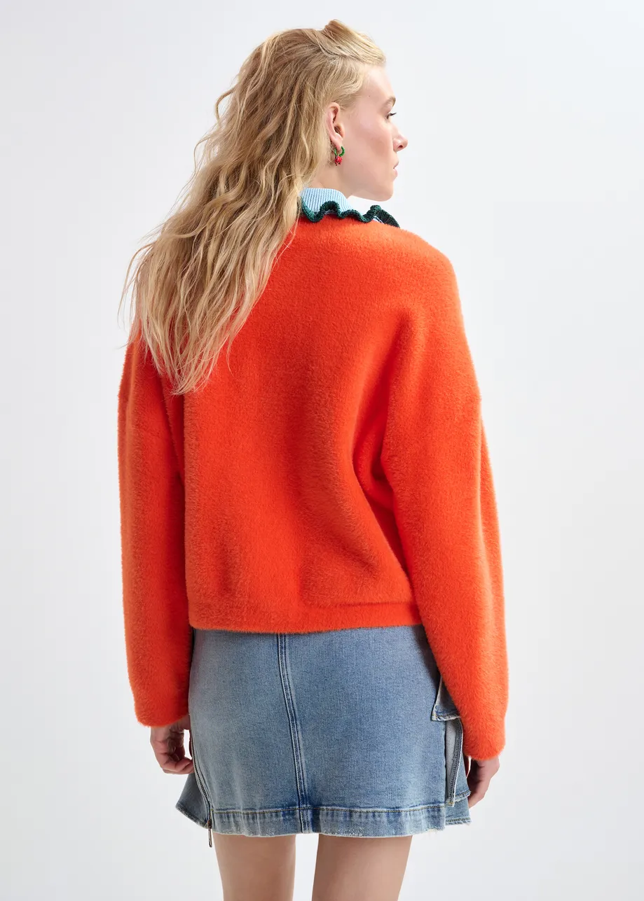 Orange cardigan with contrasting light blue and dark green ruffle collar