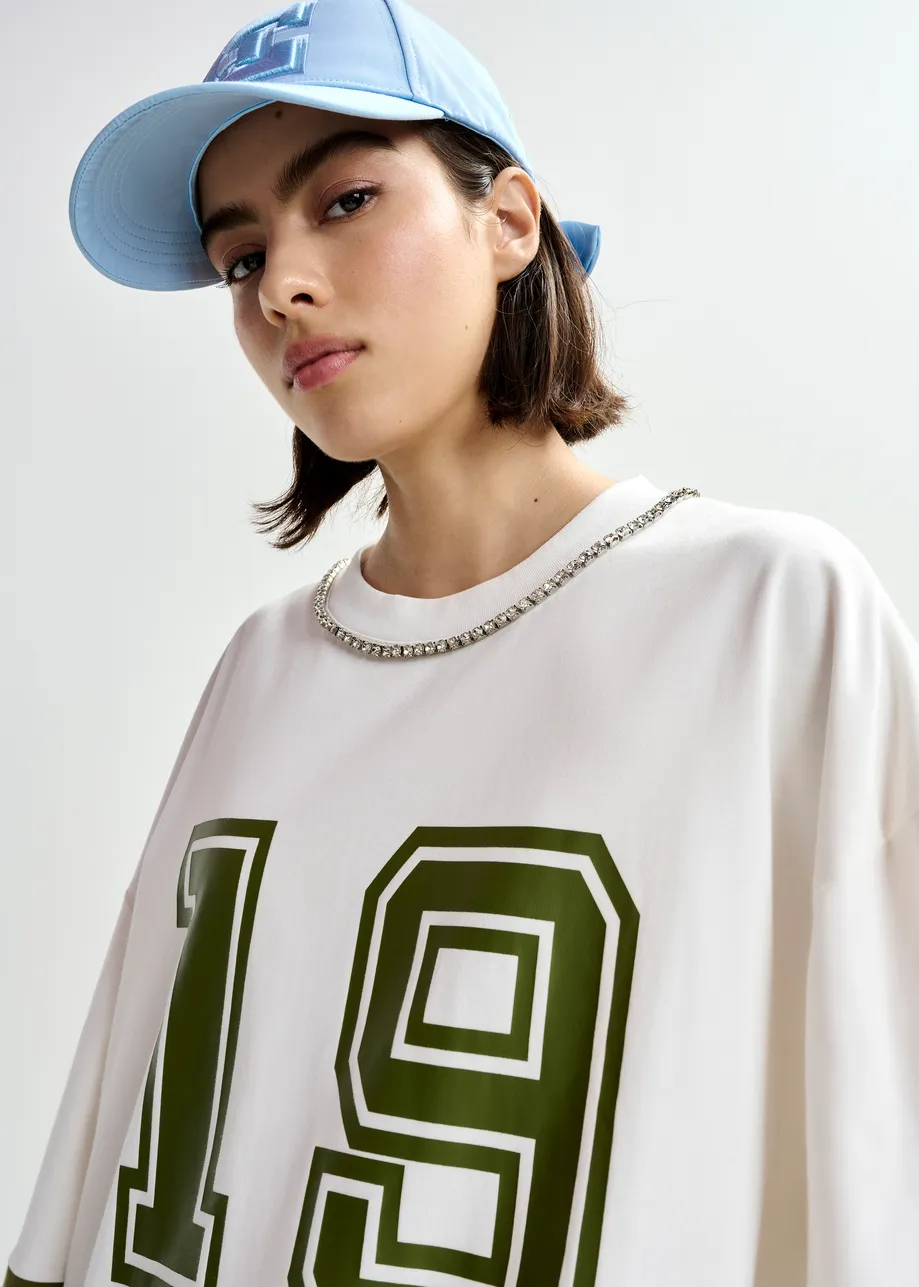 Camiseta de algodón oversize con escote adornado con strass y estampado numérico, blanco roto