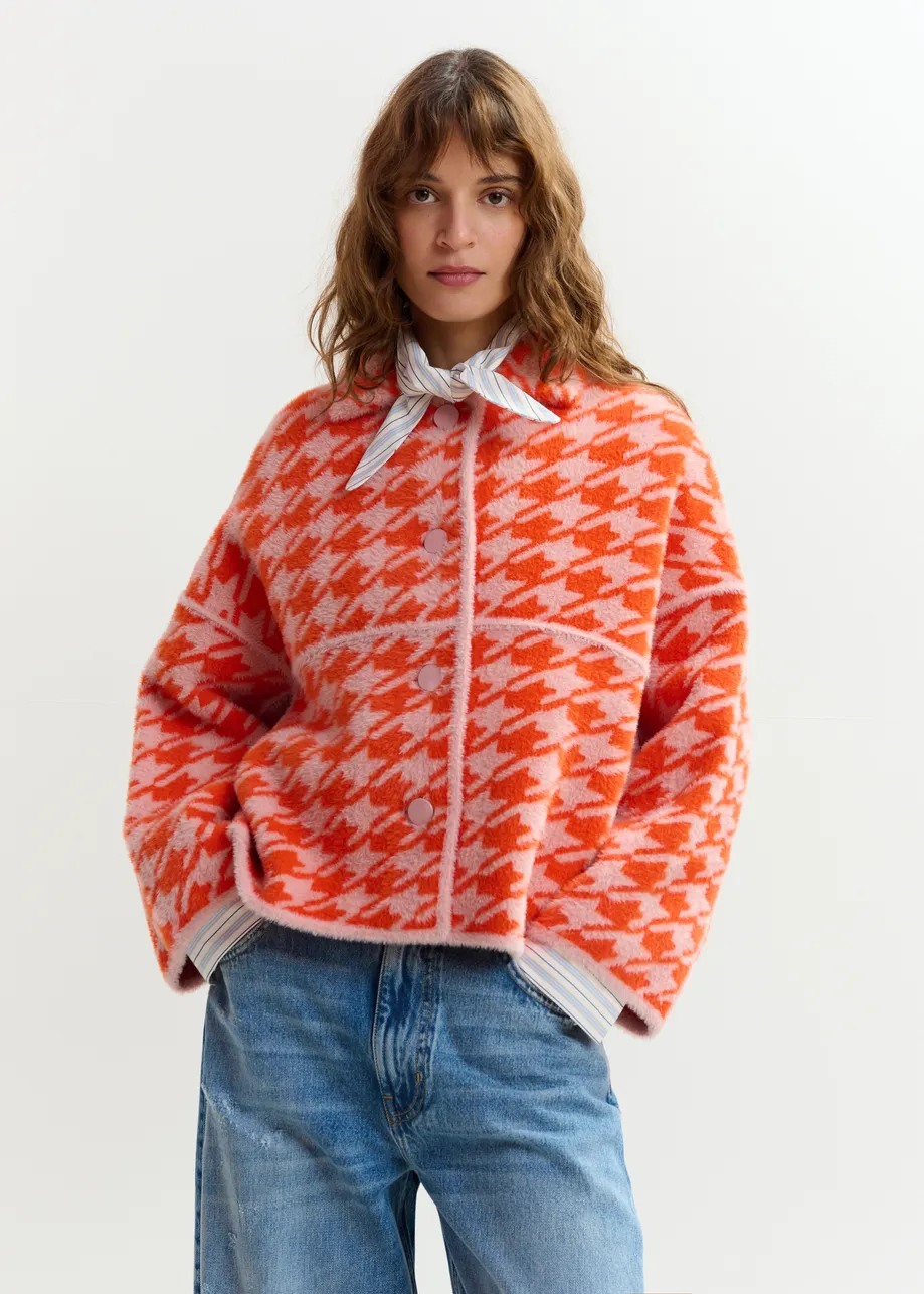 Gebreid vest met oranje en poederroze pied-de-poulepatroon