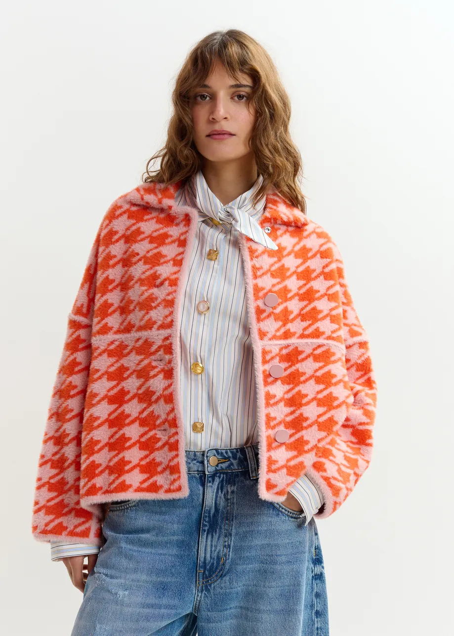 Gebreid vest met oranje en poederroze pied-de-poulepatroon