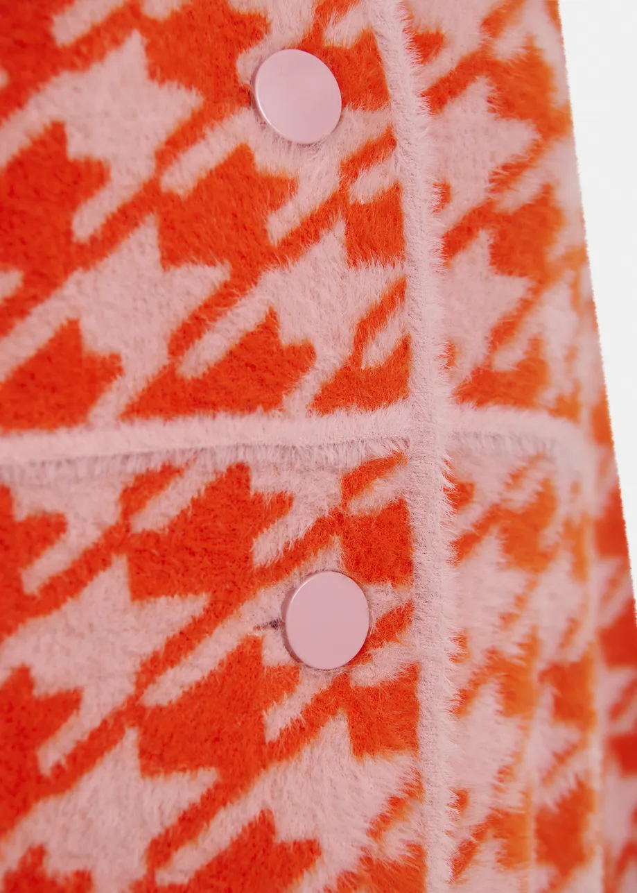 Gebreid vest met oranje en poederroze pied-de-poulepatroon