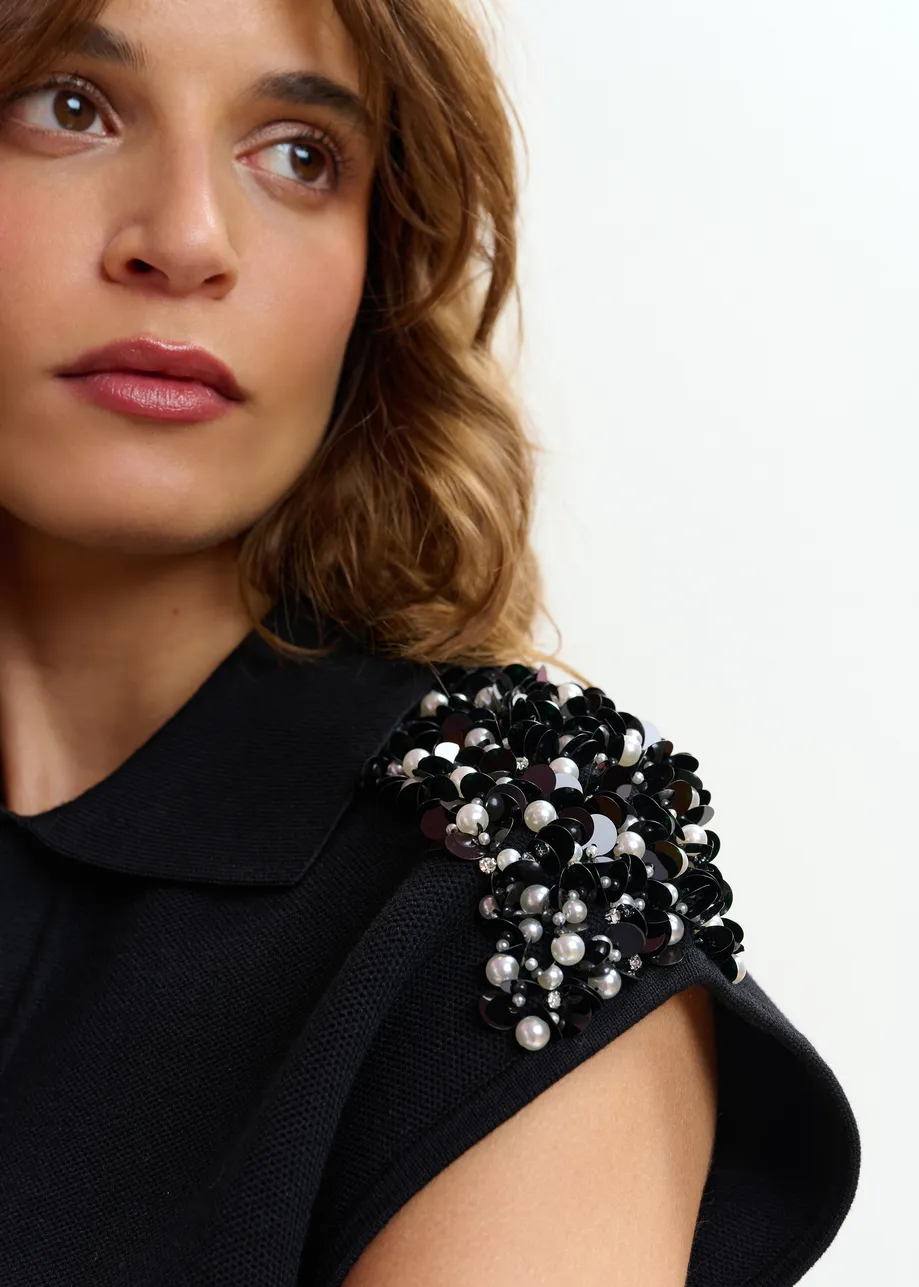 Polo negro sin mangas con hombros adornados en blanco roto