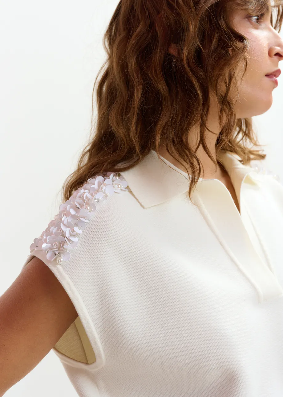 Polo blanco roto sin mangas con hombros adornados