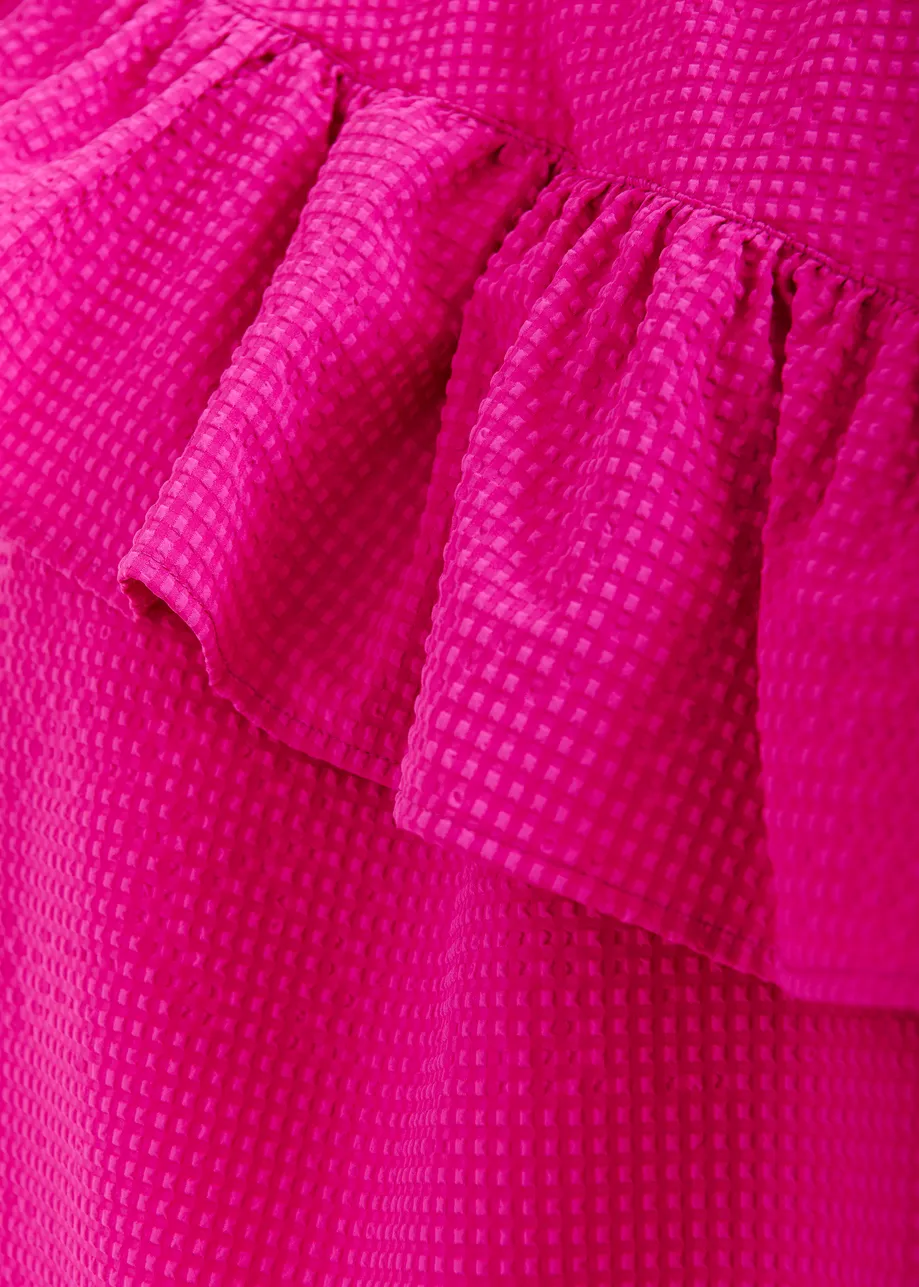 Pink asymmetrical top with ruffle details