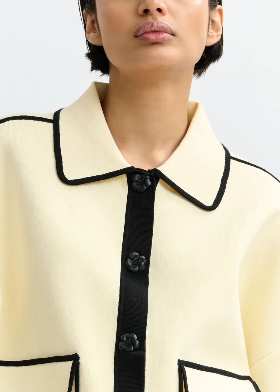 Gebroken witte cardigan met bloemetjesknopen en zwarte contrastboord