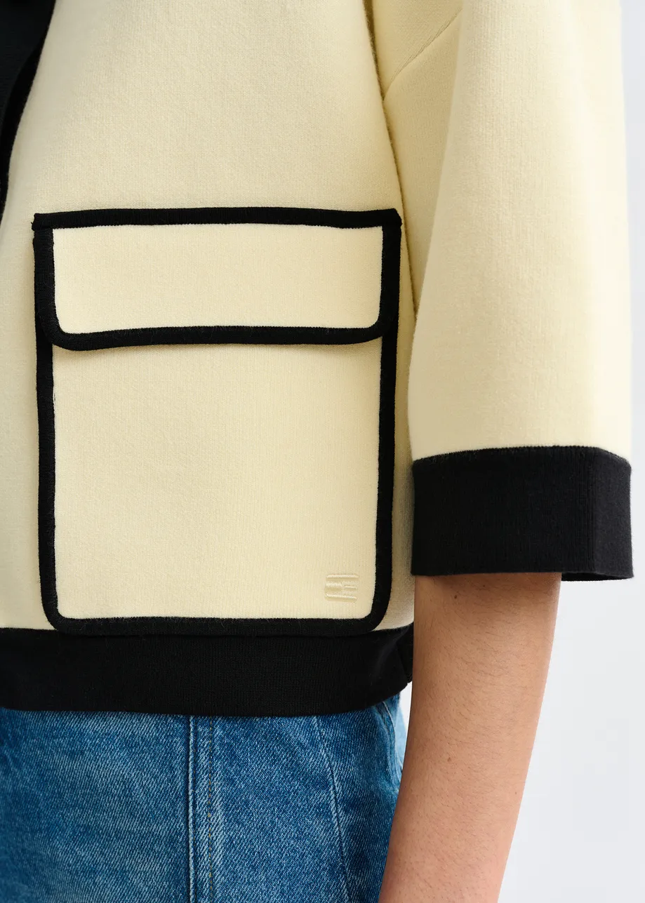 Off-white knit cardigan with flower buttons and black contrasting trims