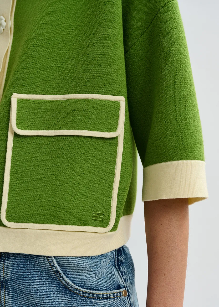 Groene cardigan met bloemetjesknopen en gebroken witte contrastboord