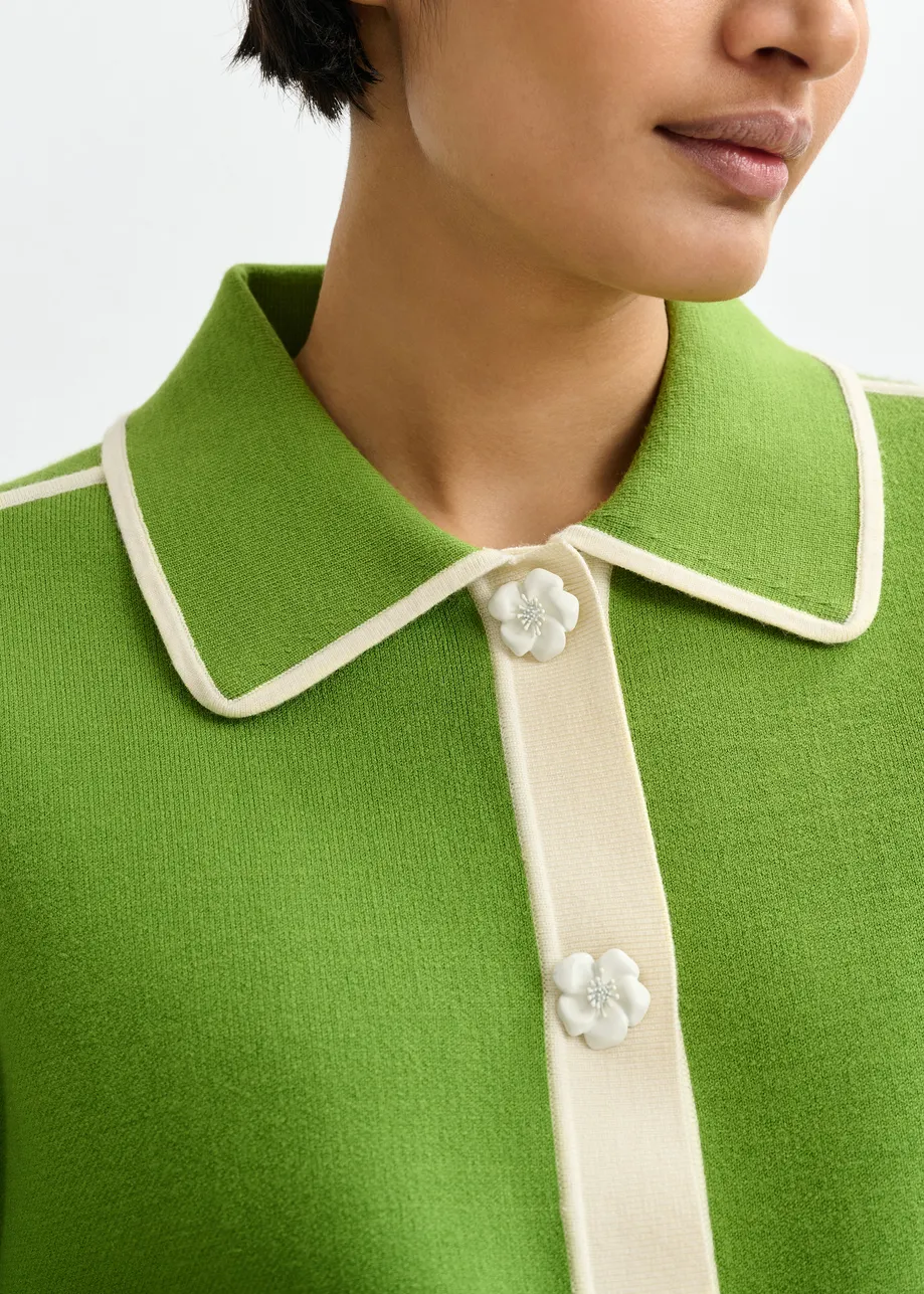 Groene cardigan met bloemetjesknopen en gebroken witte contrastboord
