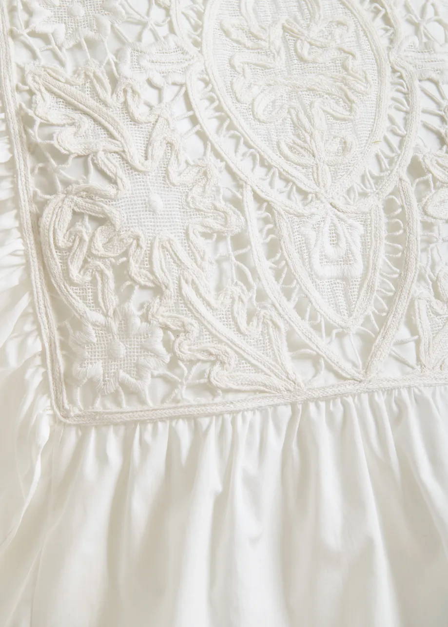 White cotton peplum top with lace-embroidered front and ruffled sleeves