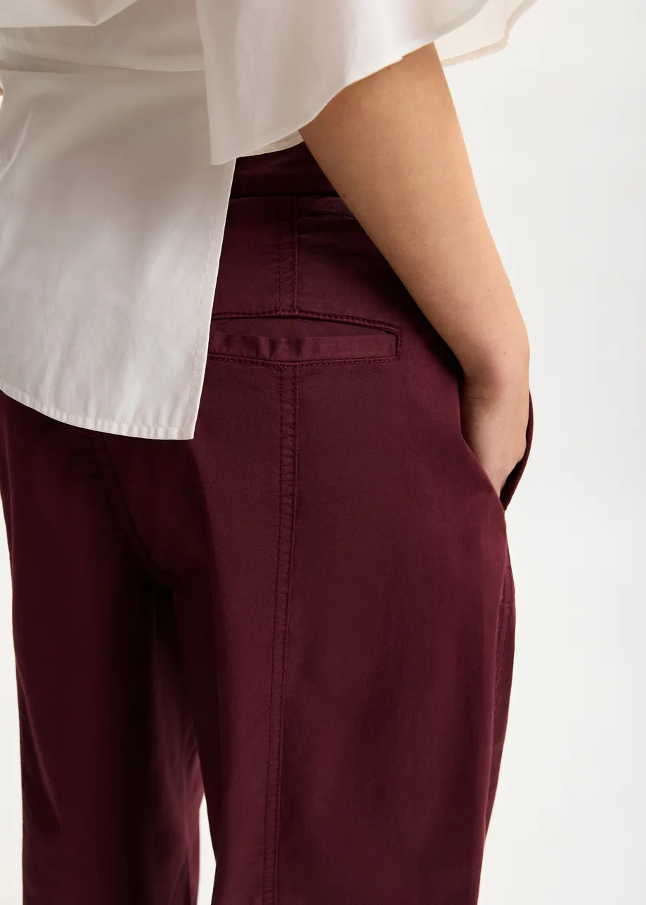 Dark red tapered cotton pants with twisted seams
