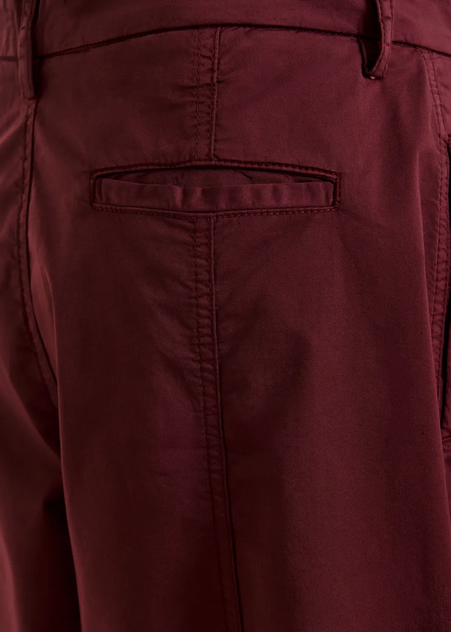 Dark red tapered cotton pants with twisted seams